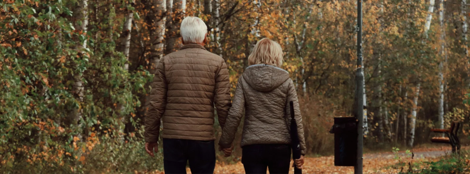 A couple walking together through an autumn estate path